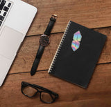 Millennial Pointy S Drawing Decal on Journal with Laptop and Watch on Wood Desk in Office