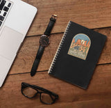 On a Dark Desert Highway Southwest Southern California Sticker on Journal with Macbook and Watch on Wood Desk in Office