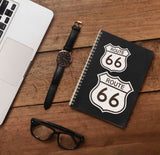 Small and Large Route 66 Sticker on Journal with Laptop and Watch on Wood Desk in Office