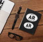 Small and Large Arkansas Stickers on Journal with Laptop and Watch on Wood Desk in Office