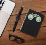 Binoculars Birdwatching Sticker on Journal with Macbook and Watch on Wood Desk in Office