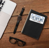 Chesapeake Virginia Sticker on Journal with Watch and Laptop on Wood Desk in Office