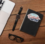 Detroit Sticker on Journal with Laptop and Watch on Wood Desk in Office