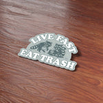 Live Fast Eat Trash Funny Feral Raccoon Bumper Sticker on Wood Desk in Office