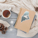 Cute Maine Snowmobile Sticker on Journal with Mug of Tea and Winter Sweater