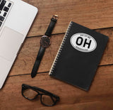 Ohio Sticker on Journal with Laptop and Watch on Wood Desk in Office