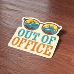 Out of Office Camping Bumper Sticker on Wood Desk in Office