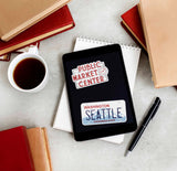 Pikes Place Sign Sticker and Seattle Washington License Plate Sticker on Kindle eReader with Books and Coffee Mug