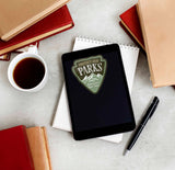 Protect Our Parks Sticker on Kindle eReader Tablet with Books and Coffee Mug