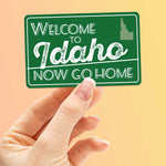 Welcome to Idaho Now Go Home Bumper Sticker on Orange Background