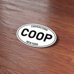 White Oval Cooperstown Upstate New York Bumper Sticker on Wood Desk in Office